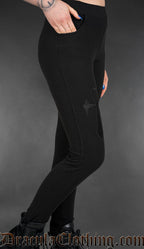 Black gothic high-waisted leggings with embroidered ankh symbols and fitted stretch silhouette worn by a model side view