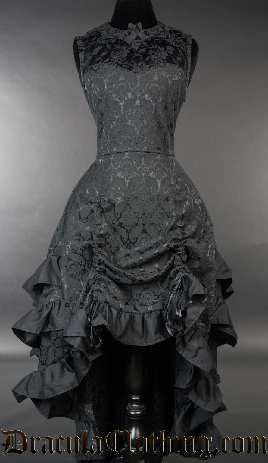 Black brocade women's dress with bustle style skirt and bat shaped collar over a sheer lace chest panel shown with bustle skirt raised in the front