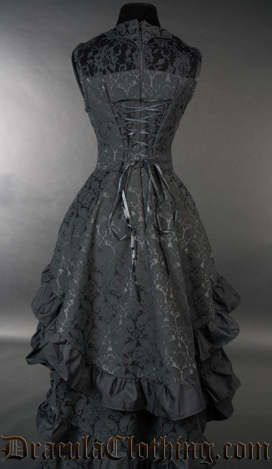Back view of women's black brocade bustle dress showing adjustable corset style lacing in the torso and layered skirt tiers