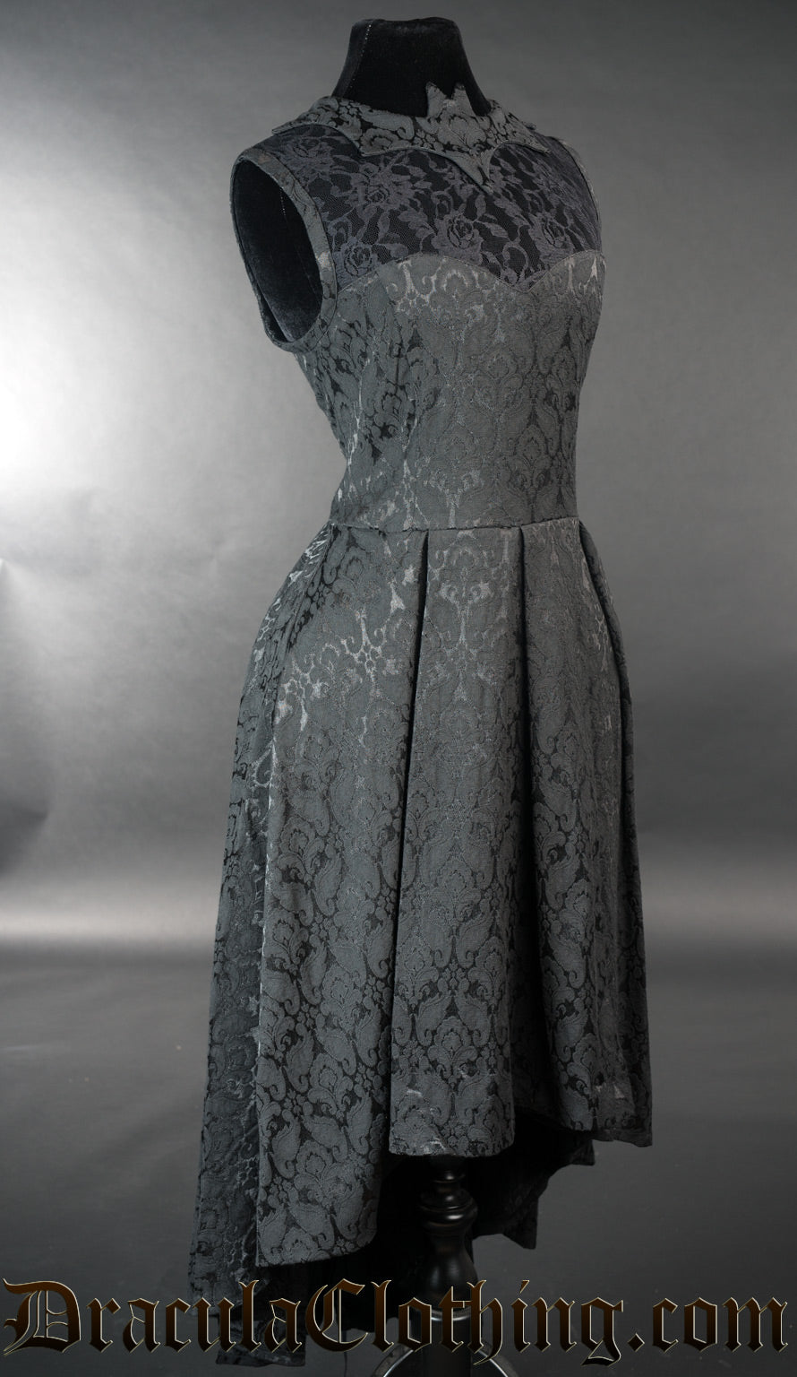 Side view of sleeveless black brocade women's dress showing high low style skirt 