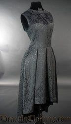 Side view of sleeveless black brocade women's dress showing high low style skirt 