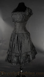 Side view of women's knee length dress made from black brocade fabric showing elasticated sleeves and bust