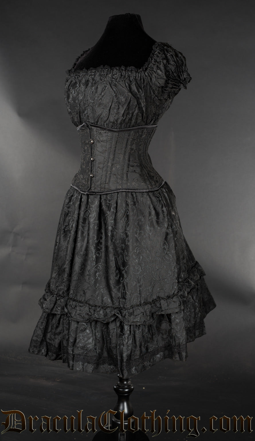 Side view of women's knee length dress made from black brocade fabric showing elasticated sleeves and bust