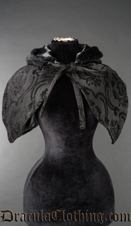 Front view of black brocade women's hood showing satin line faux fur accented hood and cape tied in the front