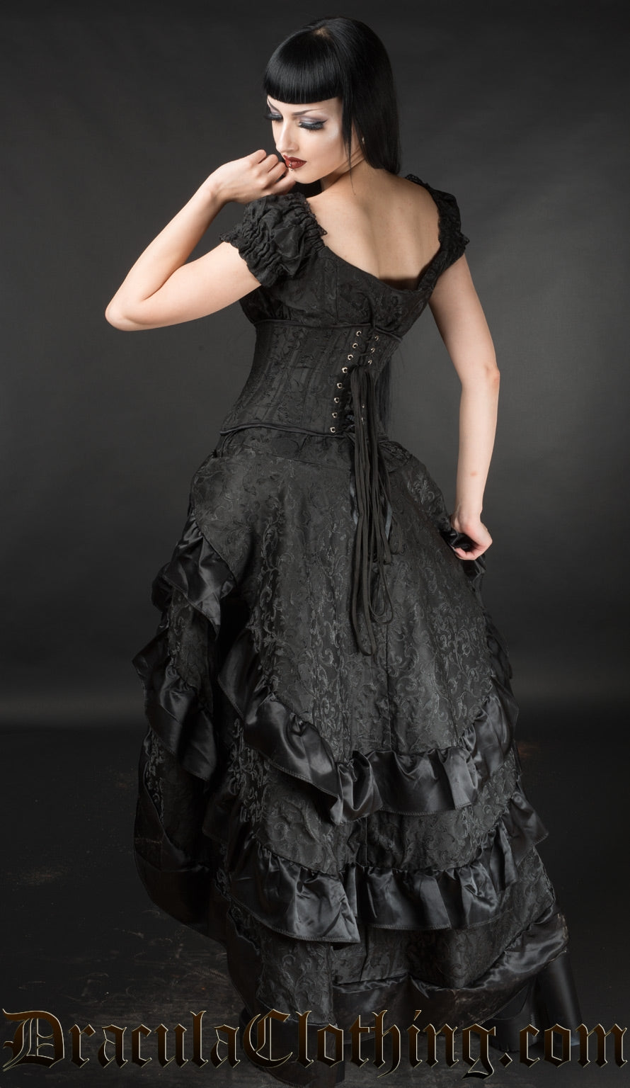 Model showing back of black brocade layer bustle skirt with additional waist cincher