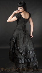 Back view of women's black brocade dress worn by model with matching bustle skirt and waist cincher