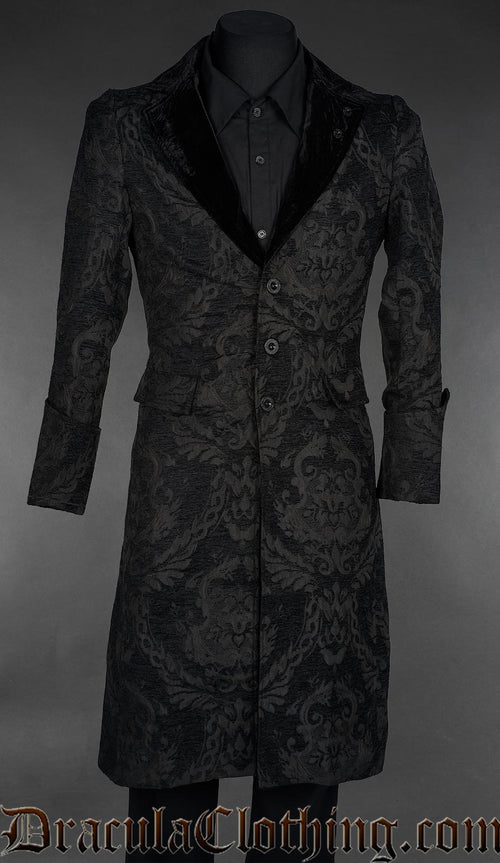 Long black chenille brocade coat with black velvet shawl lapels and a three-button front, displayed on a mannequin over a black shirt.