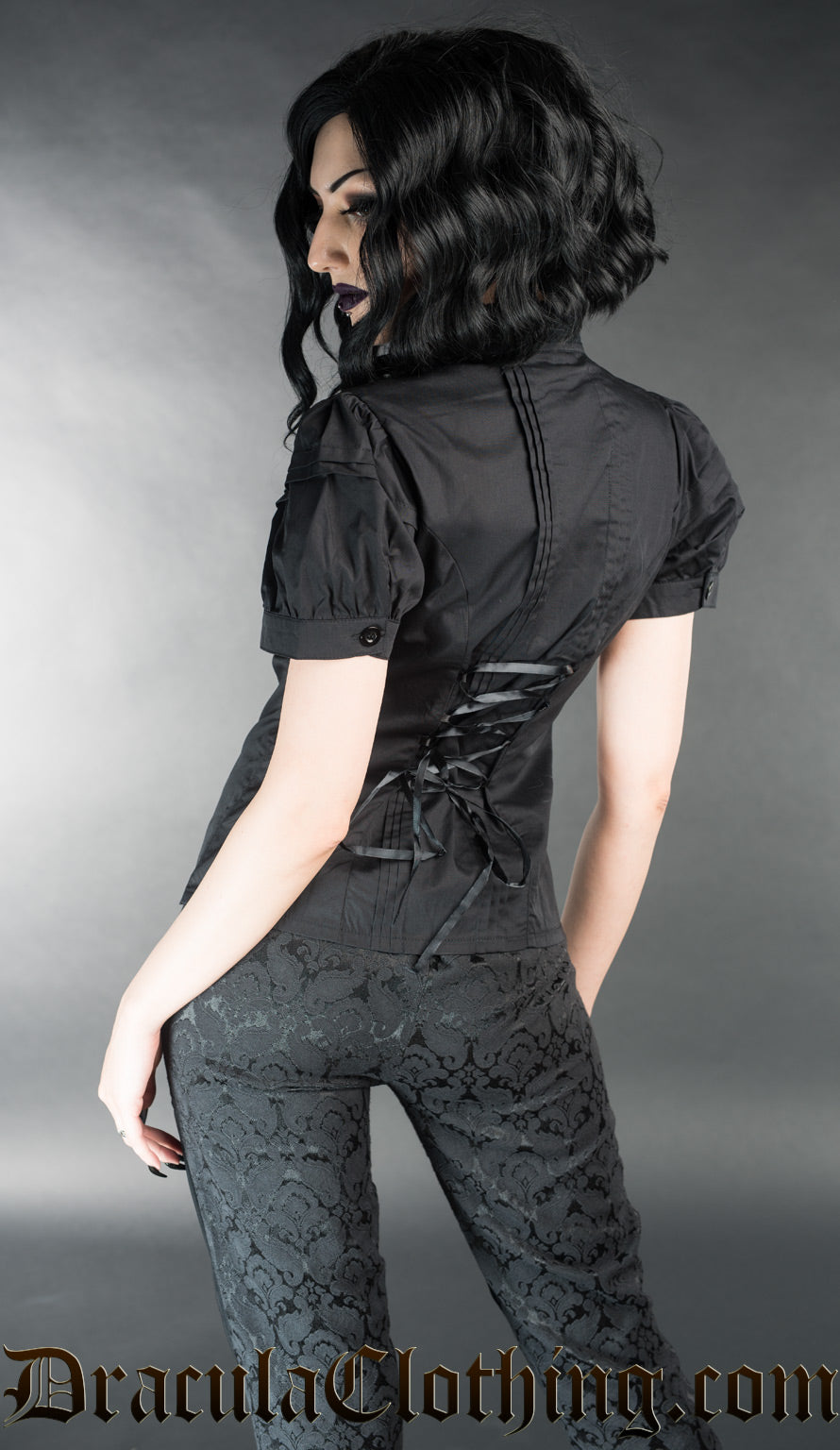 Model showing back view of women's black edwardian short sleeved blouse displaying adjustable corset style lacing in the back