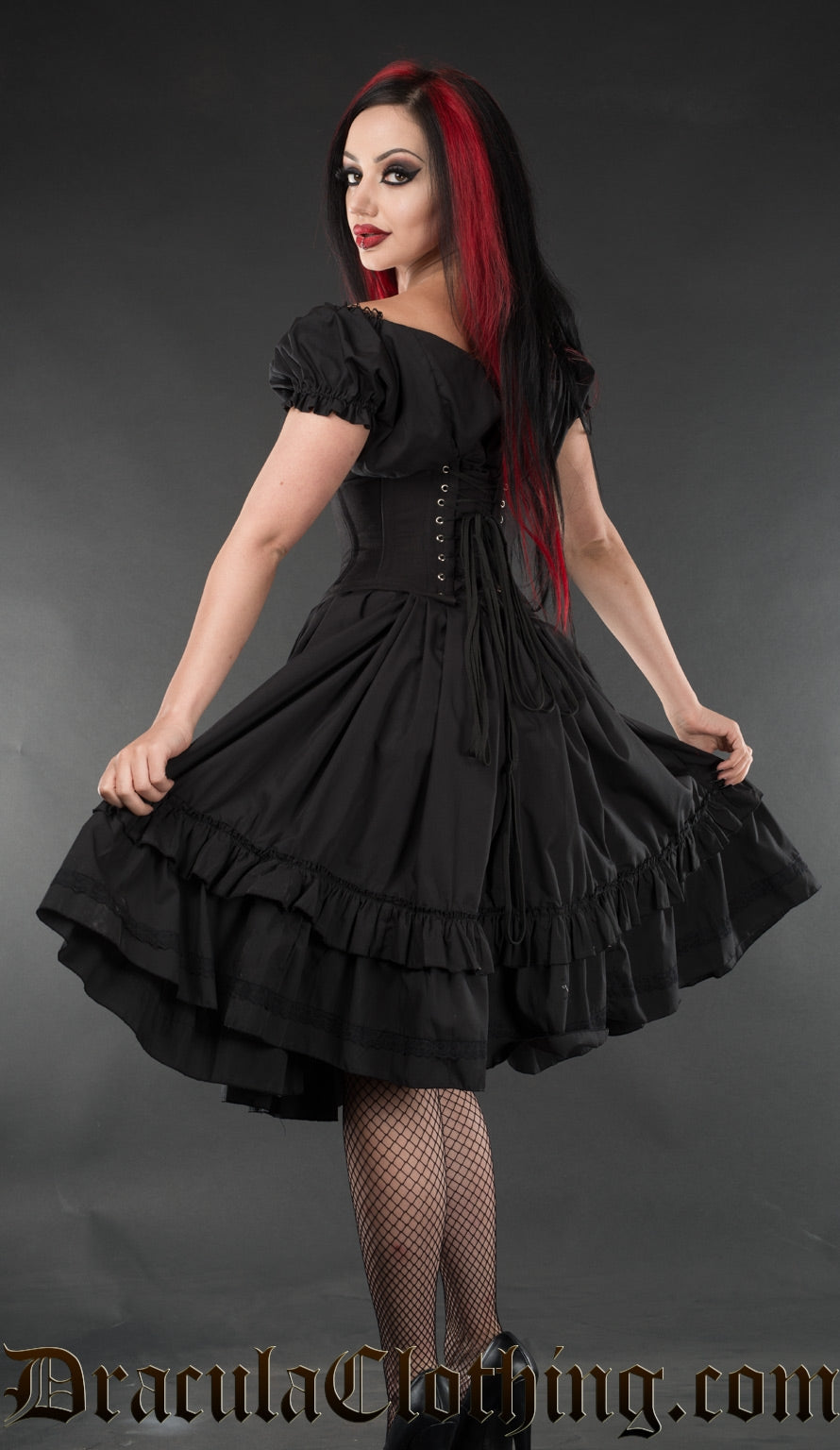 Back and side view of black women's knee length short sleeved dress worn with waist cincher showing elasticated sleeve