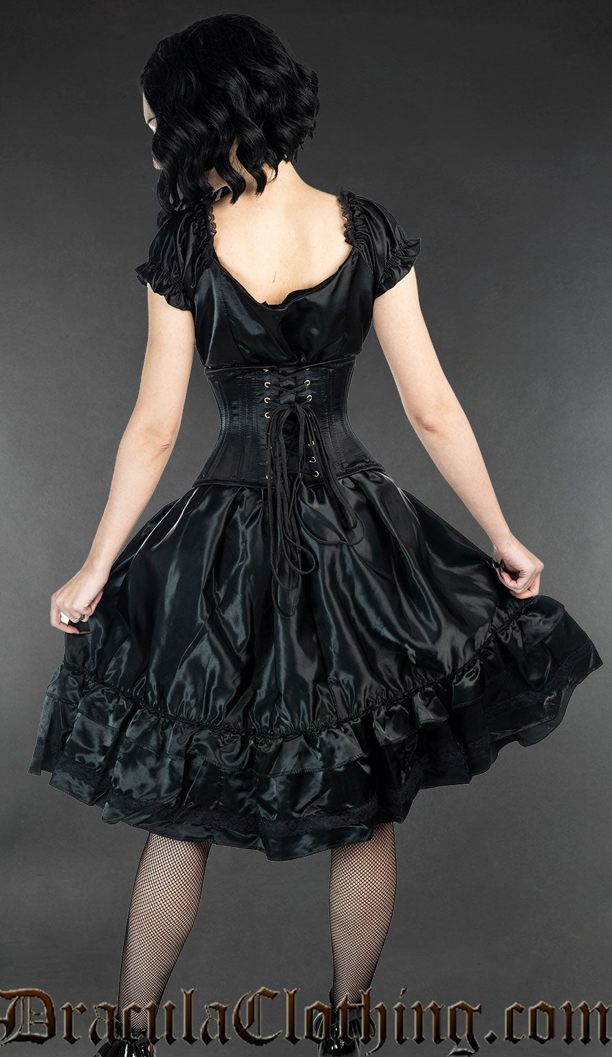 Model showing back view of black satin women's dress worn with waist cincher