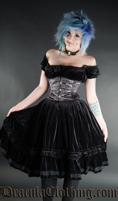 Women's black velvet knee length dress worn by a model in an off-shoulder styling