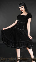 Women's knee length deep black soft velvet dress worn with a waist cincher