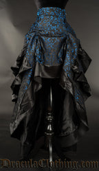 Women's layered bustle skirt made from black and blue brocade fabric with black satin hem shown raised in the front