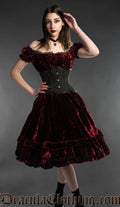 Women's knee length red bordeaux velvet dress worn by model with the sleeves in drop shoulder style and waist cincher