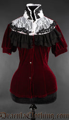 Women's red velvet blouse with black layered ruffle trim framing a white lace illusion panel on the chest