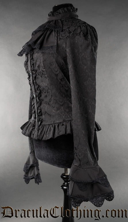 Side view of long sleeved black blouse in brocade fabric with detachable cravat and flared layered sleeve cuffs