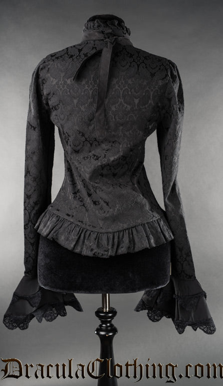 Back view of women's black brocade long sleeved blouse showing frilled hem and high collar