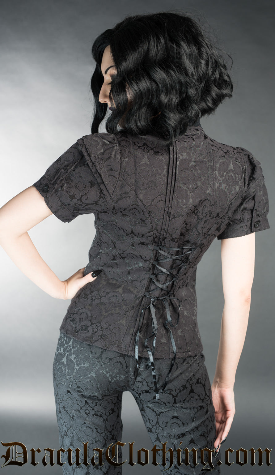 Model showing back of black brocade edwardian inspired blouse with adjustable corset style lacing in torso
