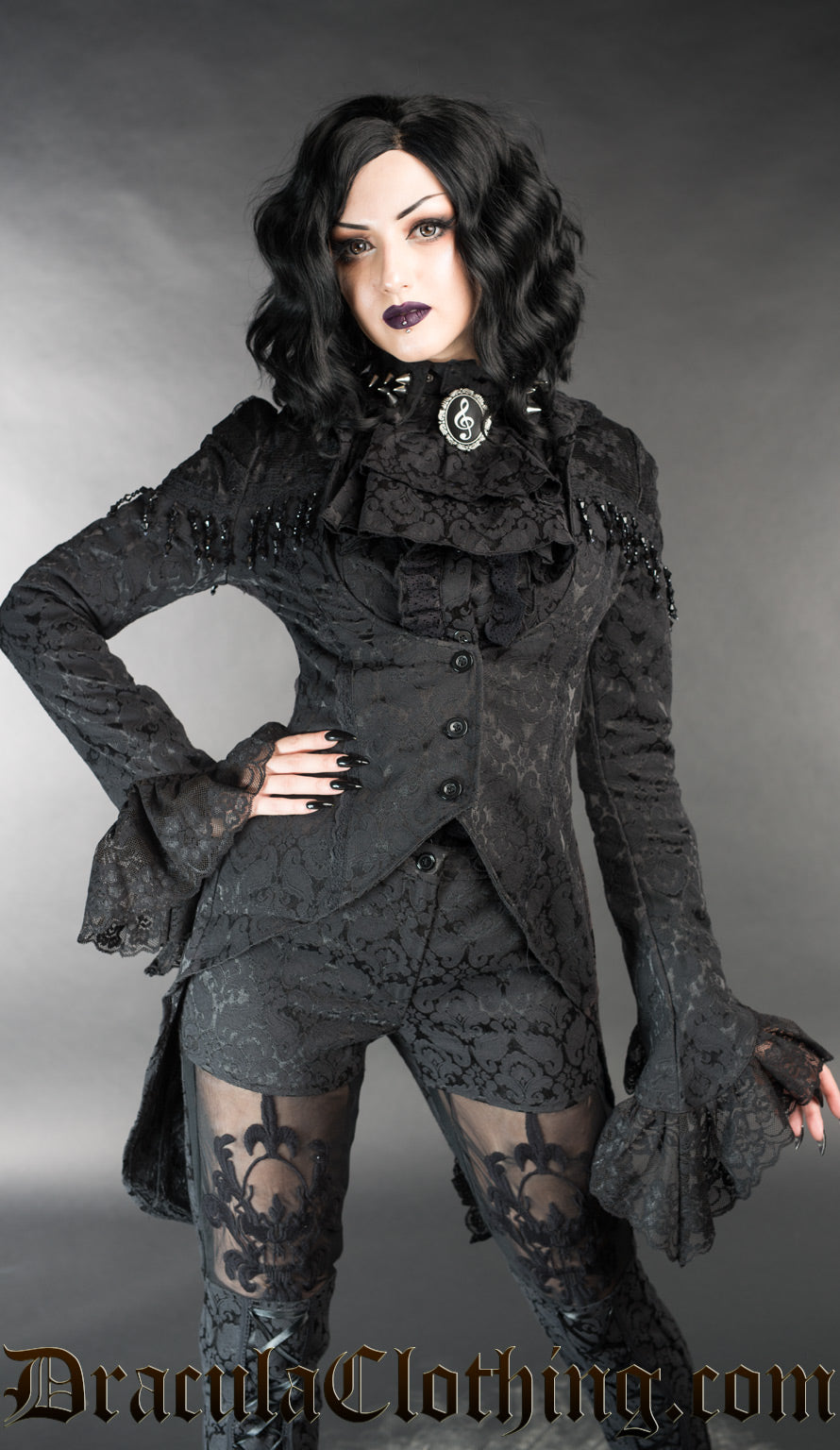 Model wearing black brocade openbust tailcoat with flared lace cuffs and beaded shoulder details over a blouse and cravat