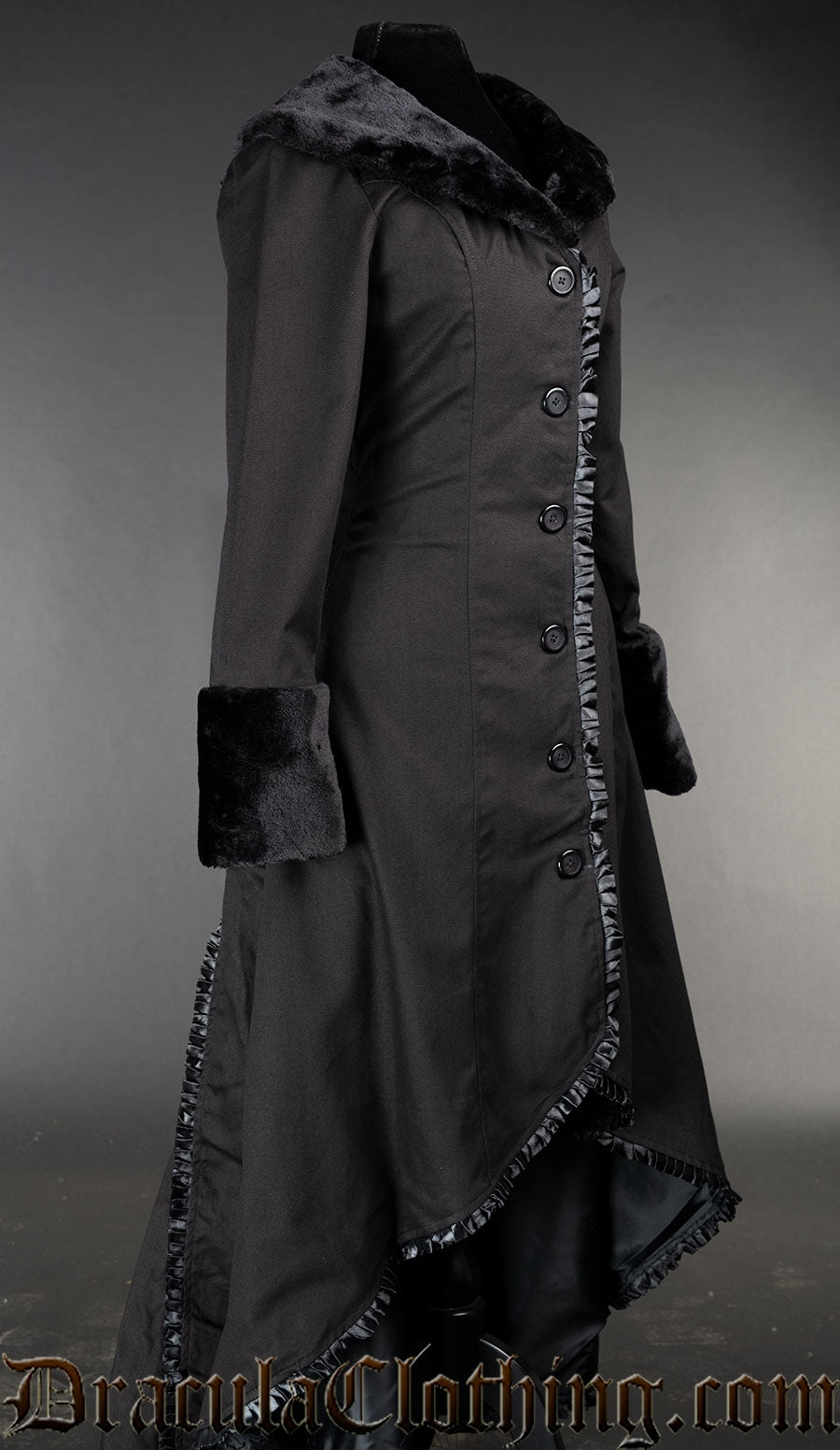 Side view of black cotton high low coat showing faux fur sleeve cuffs and black satin trim hem