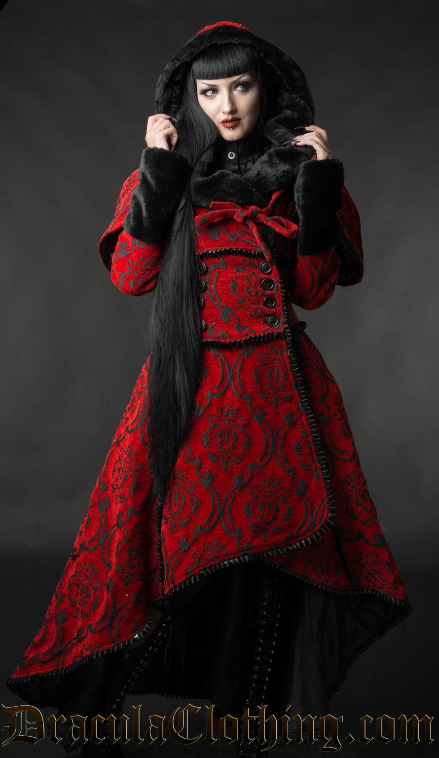 Model wearing women's black and red high low winter coat showing removable faux fur lined hood