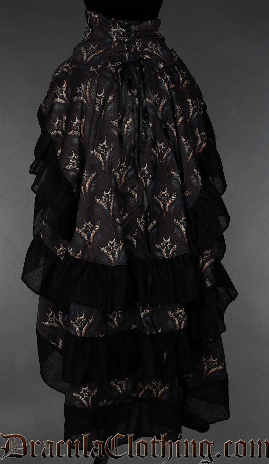 Back view of women's bustle skirt layered with printed dragon design and black cotton hem on each layer showing adjustable corset style lacing at the waist