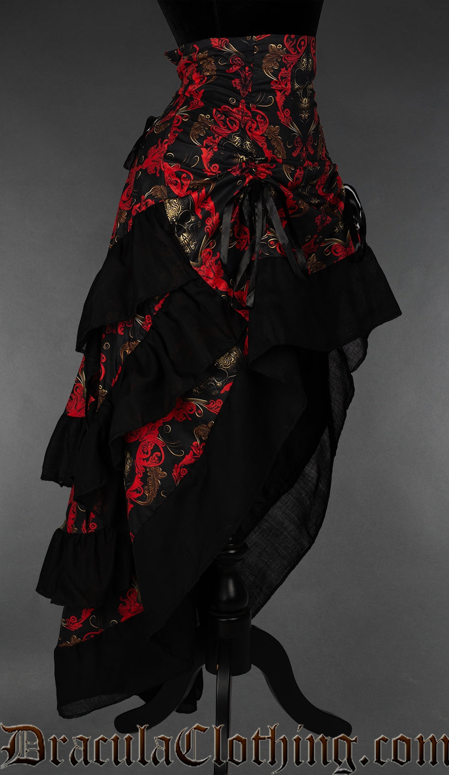 Side view of women's red and black skull print bustle skirt showing front raised and three layers of fabric in the back