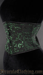 Side view of black waist cincher with woven green details in an emerald cotton brocade