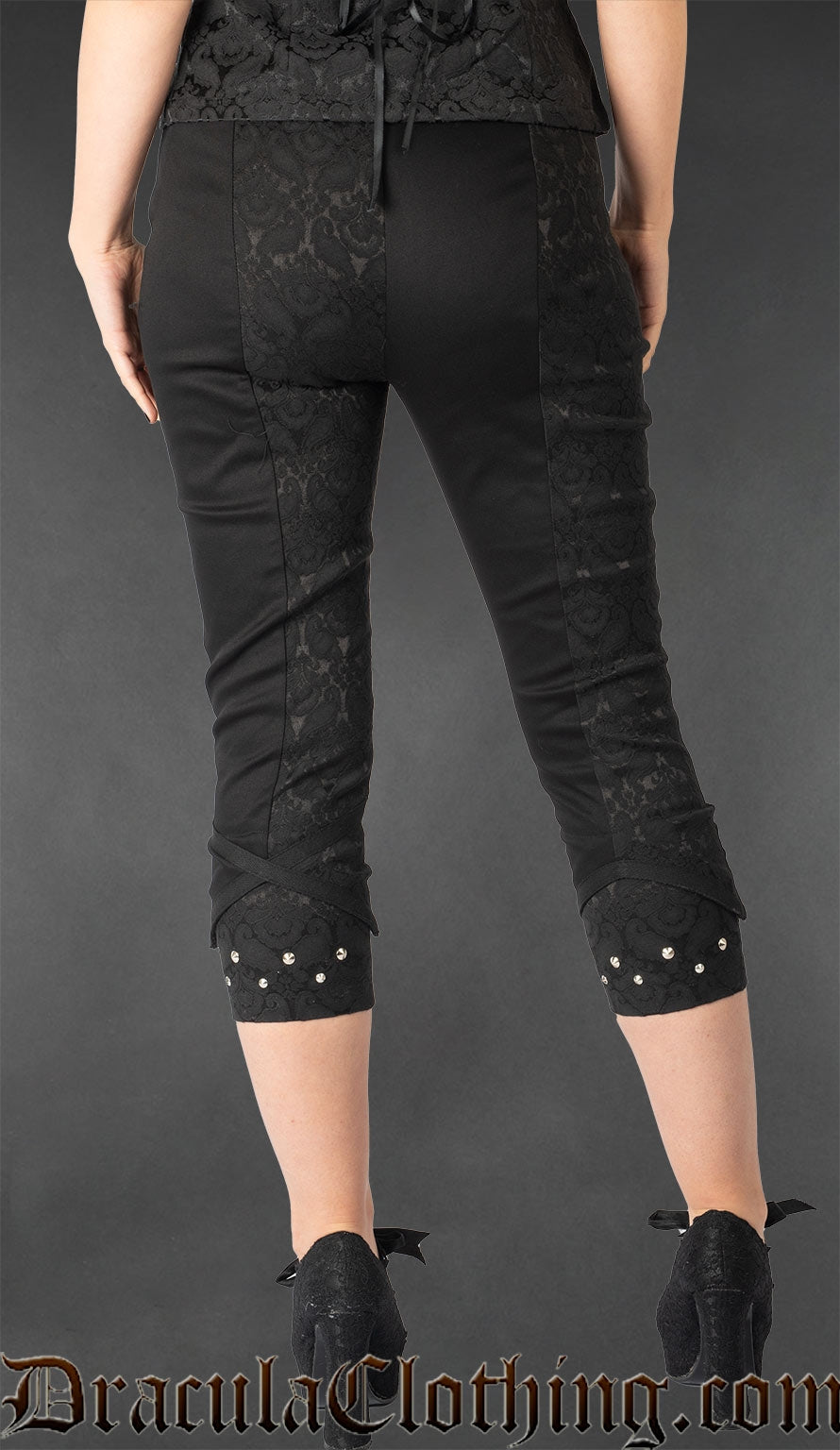 Back view of women's slim fit black brocade capris with silver stud details