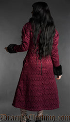 Back view of woman wearing a burgundy gothic brocade coat with black faux fur collar and cuffs on a gray background