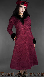 Back view of woman wearing a burgundy gothic brocade coat with black faux fur collar and cuffs on a gray background
