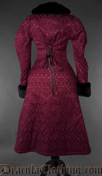 Back view of burgundy gothic brocade coat with lace-up waist and black faux fur collar and cuffs on a gray background