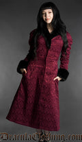 Front view of burgundy gothic brocade coat with black faux fur trim worn by a model on a gray background