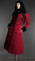 Red gothic brocade coat with black faux fur trim worn by a woman on a gray background