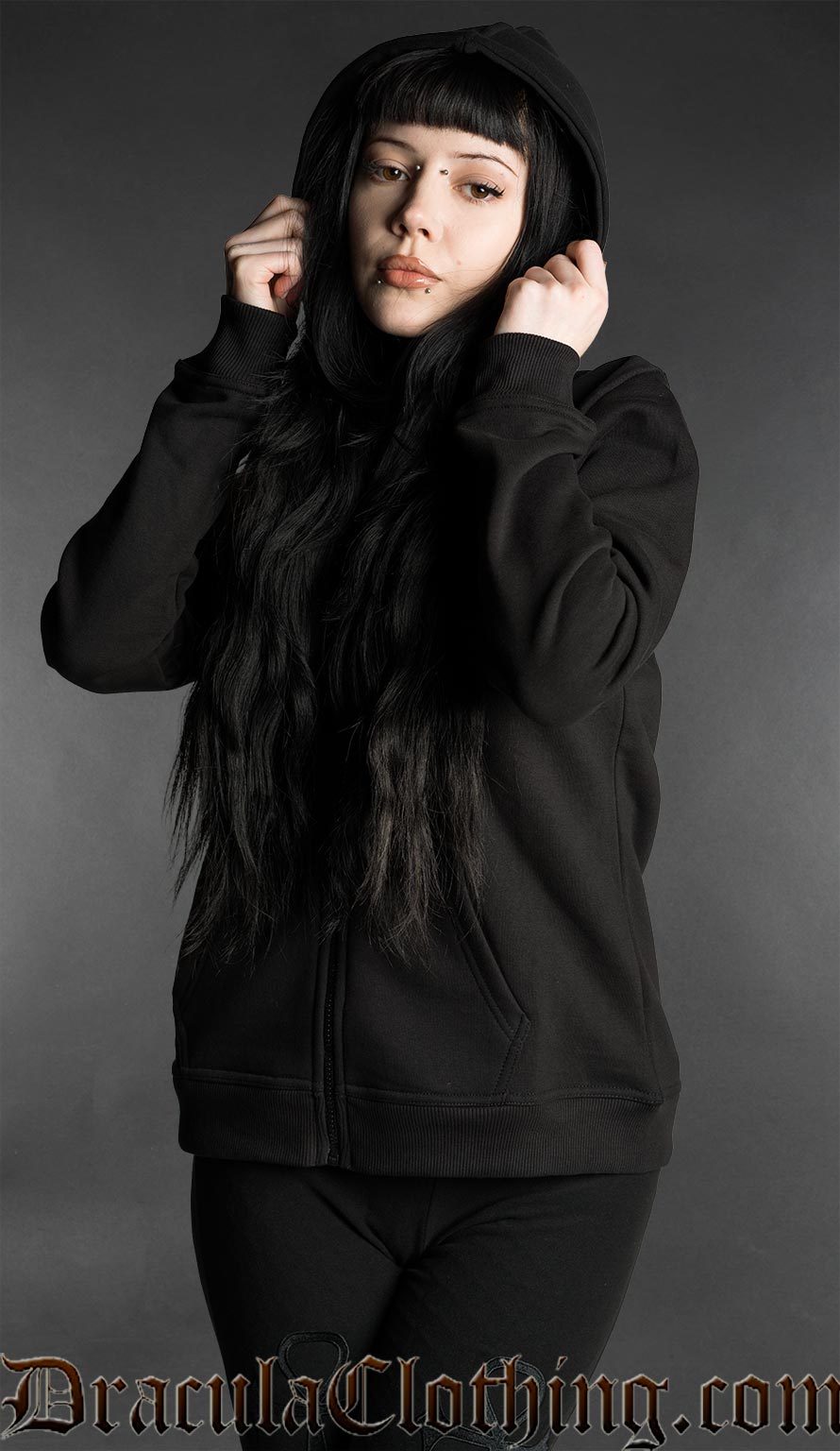Woman wearing a black gothic zip hoodie with hood up in minimalist dark fashion style