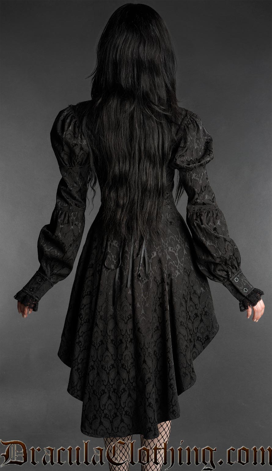 Woman wearing a black neo-Victorian brocade dress with sweetheart neckline, puff sleeves and high-low hem back view