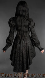 Woman wearing a black neo-Victorian brocade dress with sweetheart neckline, puff sleeves and high-low hem back view