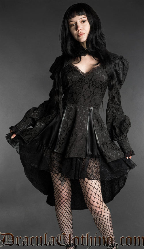 Woman wearing a black neo-Victorian brocade dress with sweetheart neckline, puff sleeves and high-low hem
