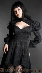 Woman wearing a black neo-Victorian high-low dress with floral brocade fabric, sweetheart neckline and puff bishop sleeves detailed view