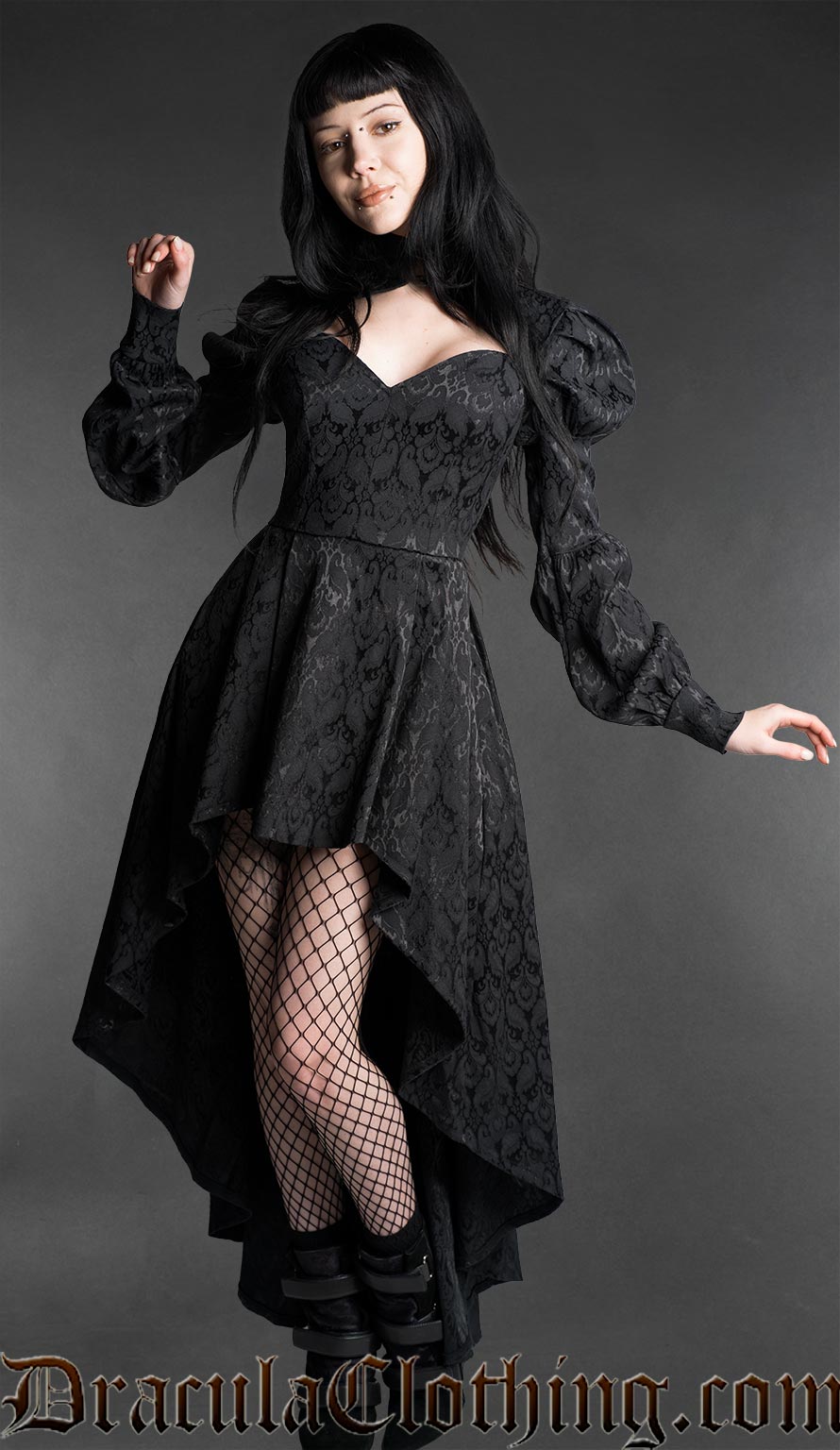 Woman wearing a black neo-Victorian high-low dress with floral brocade fabric, sweetheart neckline and puff bishop sleeves