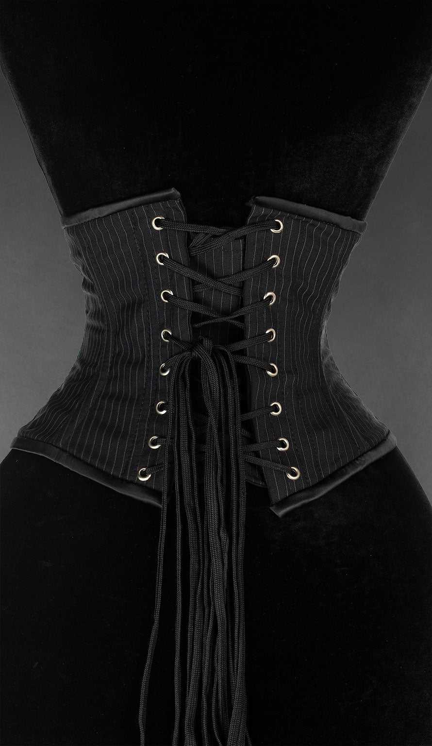 Back view of black pinstripe patterned waist cincher showing adjustable lacing and modesty panel in matching fabric