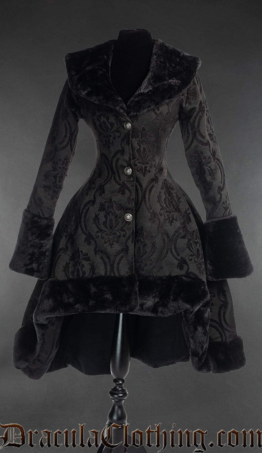 Women's thick winter coat made from black cotton brocade fabric in a damask pattern with short high low hem and faux fur accents on collar cuffs and hem