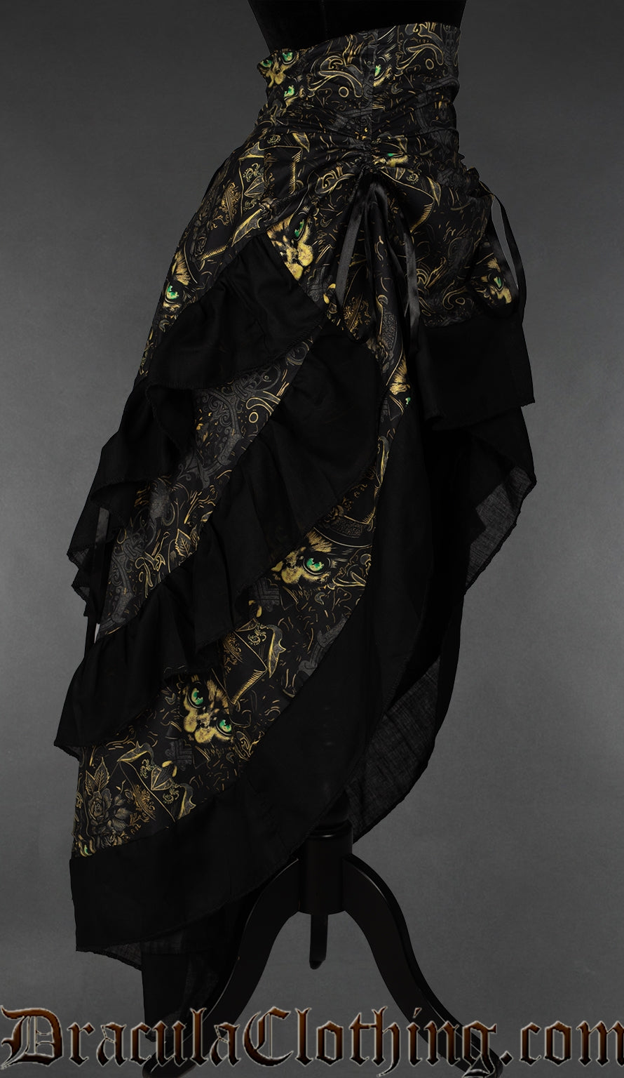 Side view of women's layered bustle skirt printed with a top hat wearing cat in a gold and black toned multicolour print showing more layers in the back than front