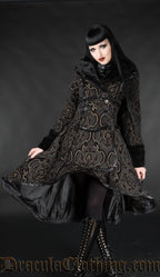 Model wearing short high low coat made from black and gold cotton jacquard in a damask pattern and faux fur accents