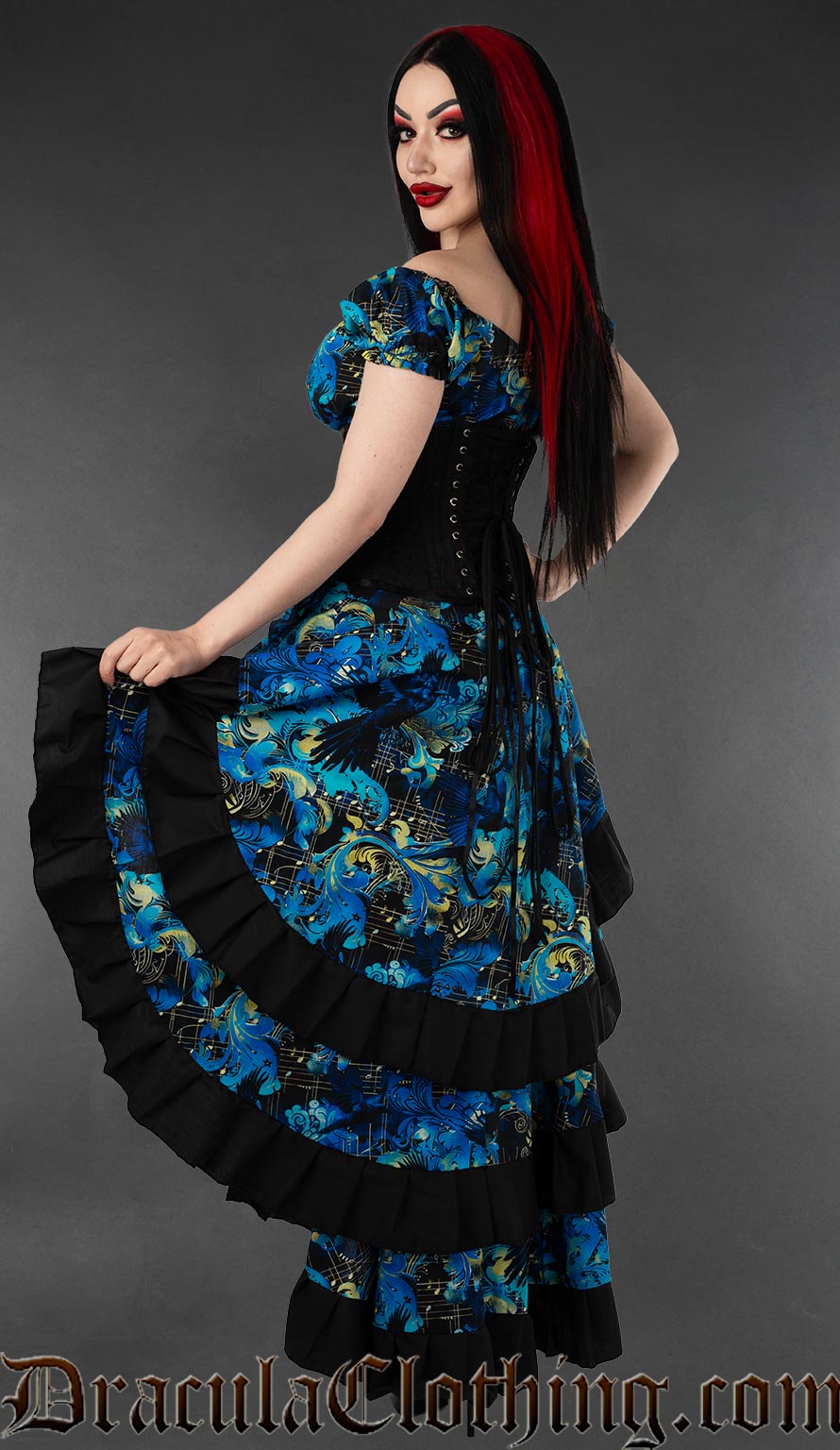 Back and side view of a women's layered bustle skirt in a blue raven and music inspired print with black cotton hem trim