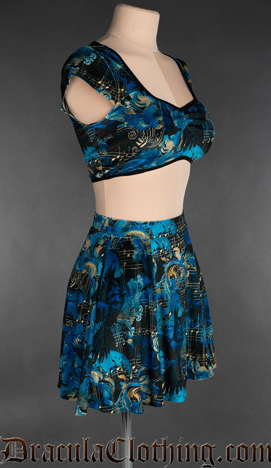 Side view of women's velvet short skirt with elasticated waistband in a blue and black raven and sheet music inspired print 