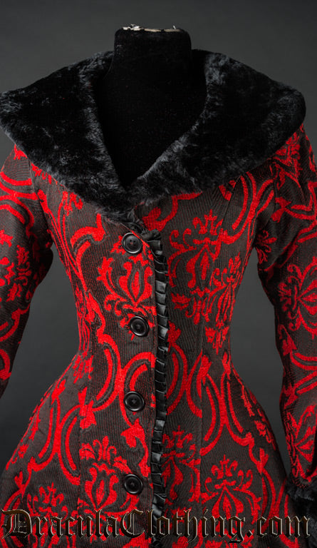 Close up of front of women's red and black brocade winter coat showing ruffled satin trim hem and black faux fur collar details