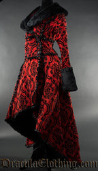 Side view of women's red and black brocade winter coat with faux fur accents showing high low style hem