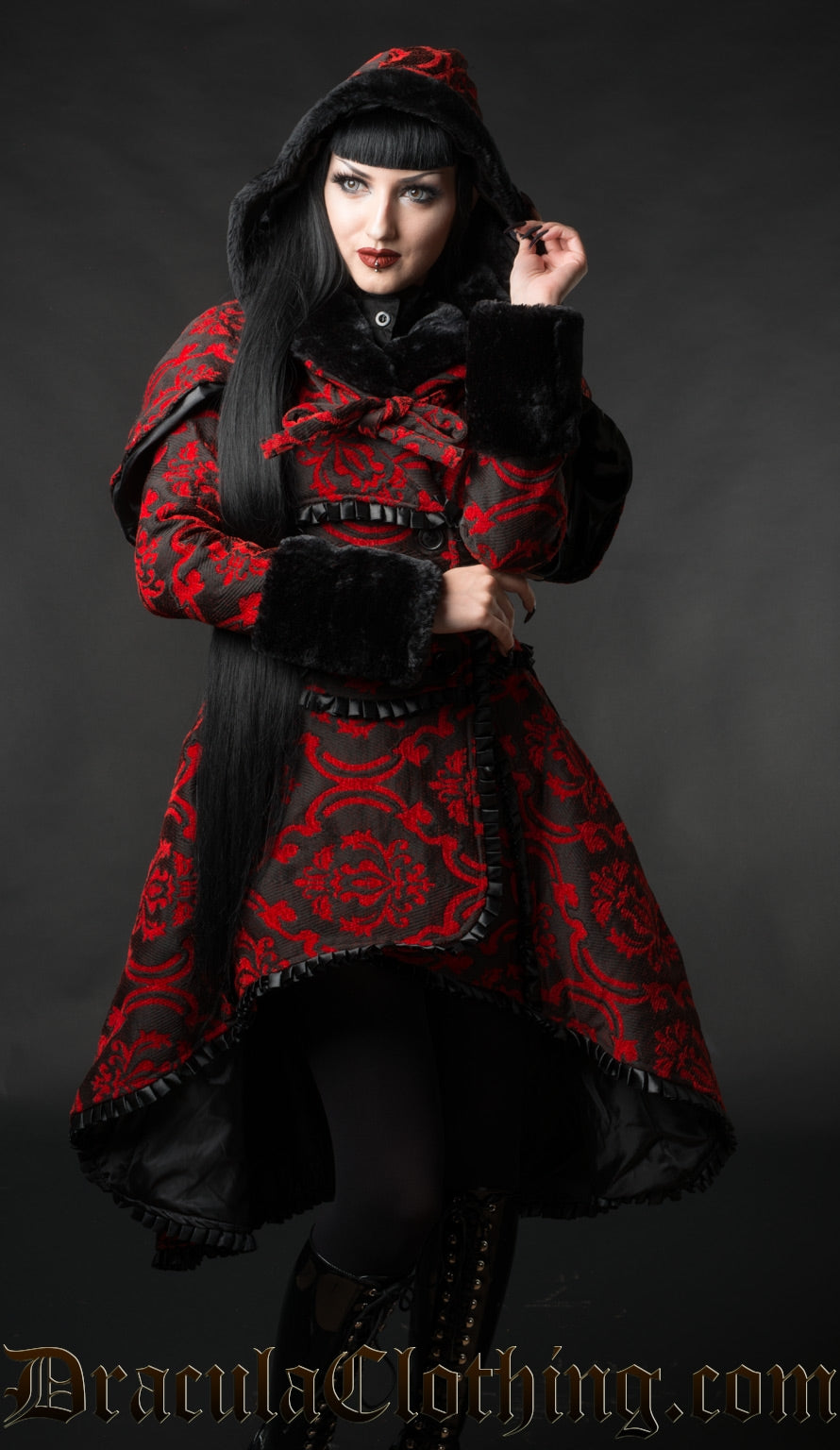 Model wearing red and black winter women's coat with matching detachable cape and hood