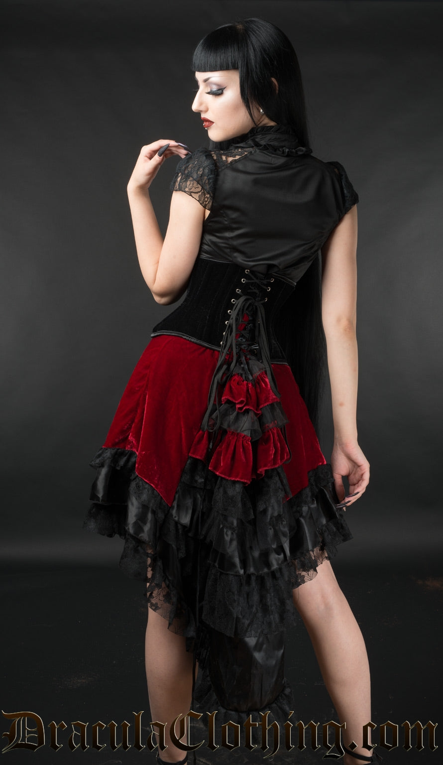 Back view of model wearing red velvet EGL high low skirt showing longer length at the back and tiered ruffles of fabric